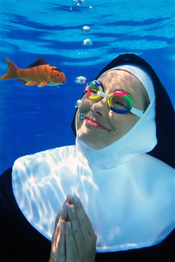 nun in goggles underwater and looking at a goldfish