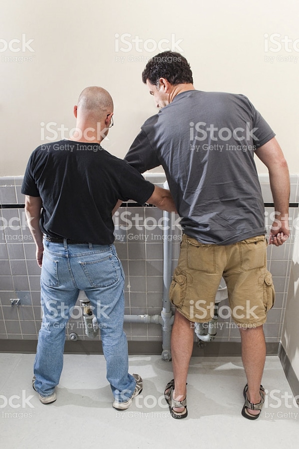 man helping another man pee WTF stock photos